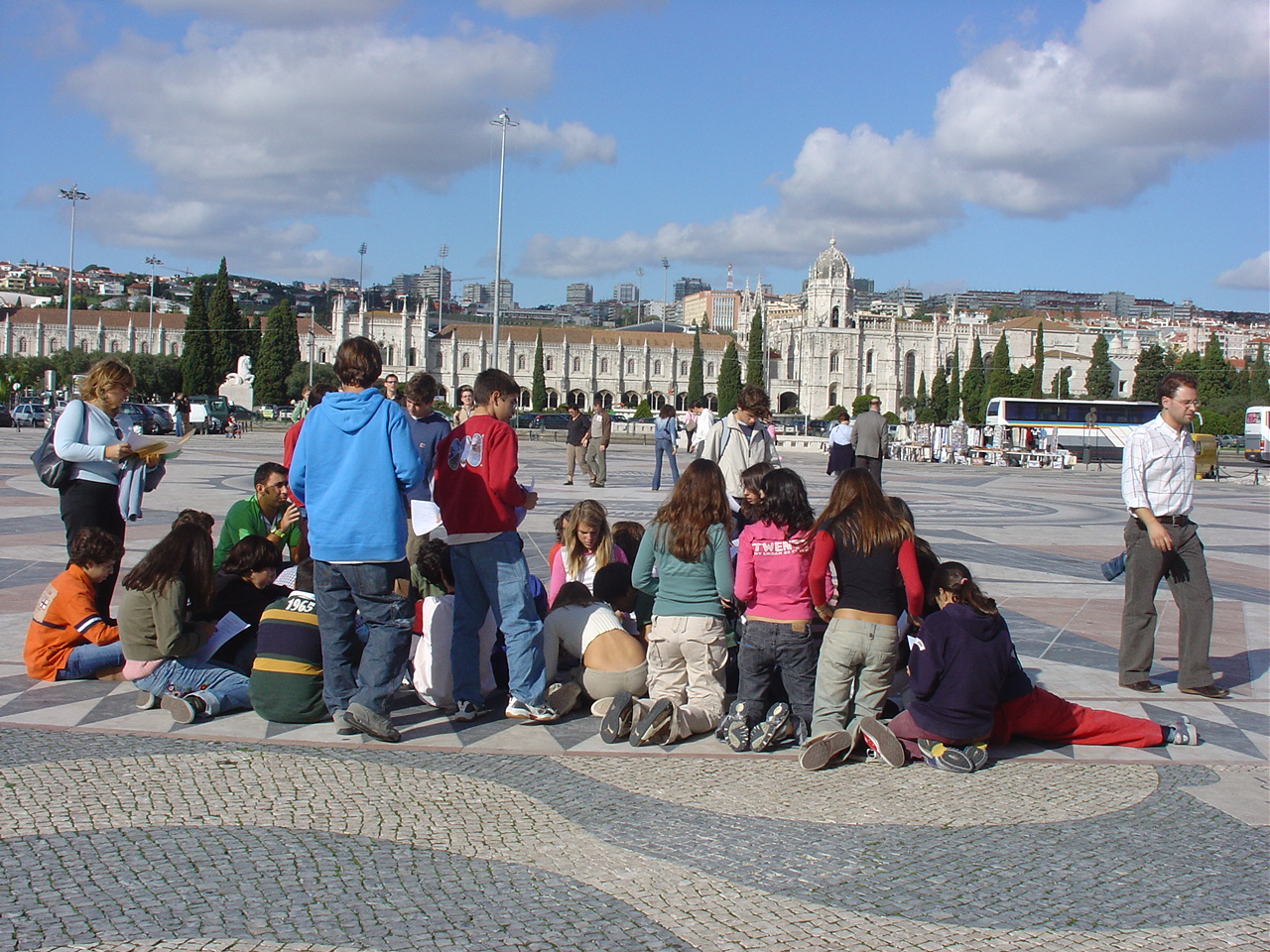 Na Rosa-dos-ventos várias pessoas sentadas no chão, ouvem a descrição da origem do monumento e o que significa